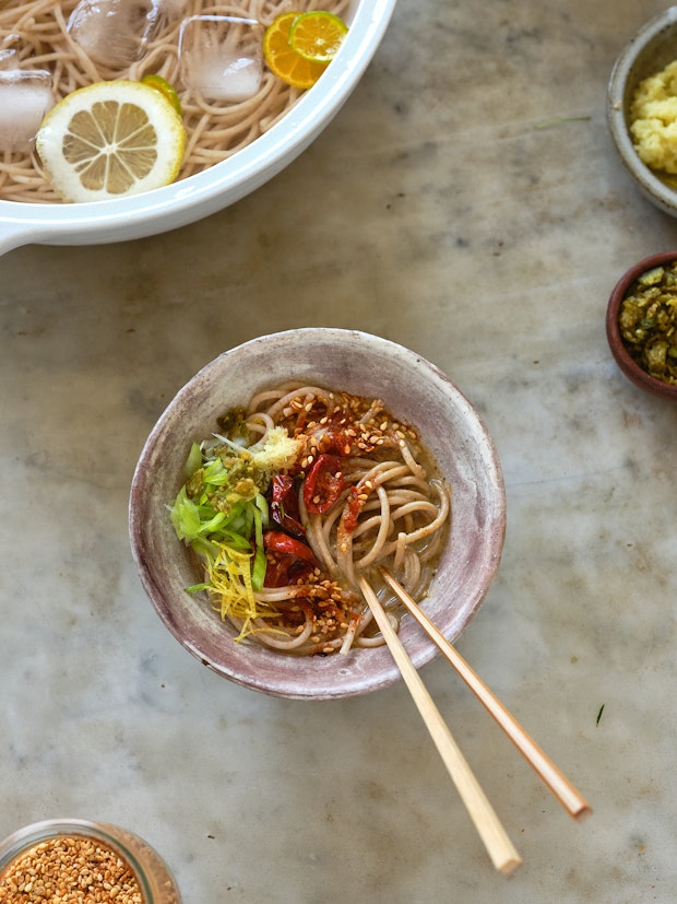 sesame noodles in a bowl surrounded by a variety of toppings