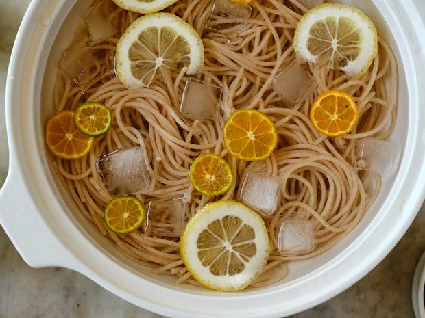 noodles in ice water with ice cubes and citrus slices