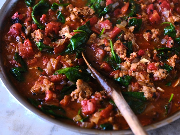 red sauce for baked ziti in a skillet with a wooden spoon