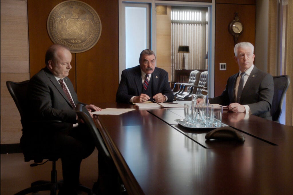 Frank has a meeting with Sid and Garrett at a long table on Blue Bloods Season 14 Episode 12