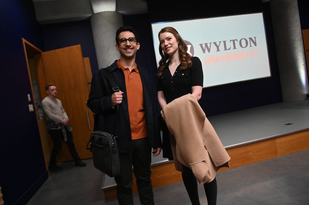 Rizwan and Phoebe standing in a lecture hall holding bags and coats on The Irrational Season 2 Episode 1