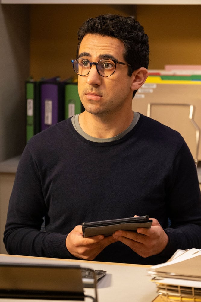 Rizwan holding a tablet and looking surprised on The Irrational Season 2 Episode 2