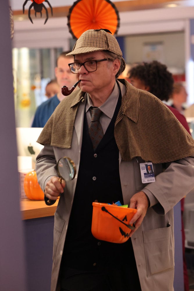 Dr. Charles dressed as Sherlock Holmes with a deerskin cap and pipe and holding a small treat bowl on Chicago Med Season 10 Episode 5