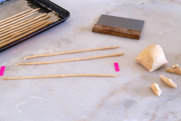 Rolling out grissini dough on a marble counter top