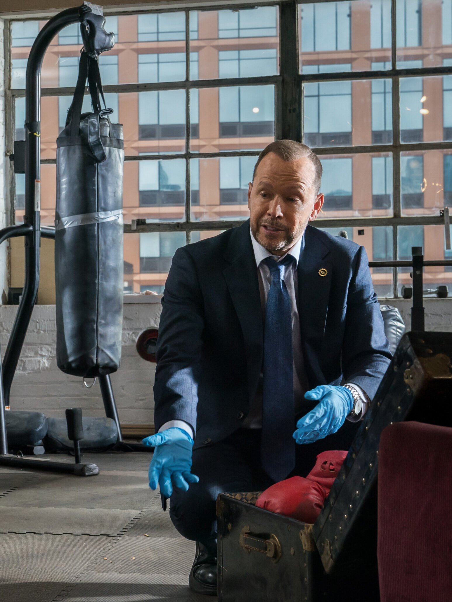 Danny and Baez searching for evidence in a fighter's apartment on Blue Bloods Season 14 Episode 15