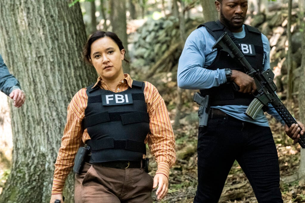 Hana and Ray walking through the woods with guns drawn on FBI: Most Wanted Season 6 Episode 3