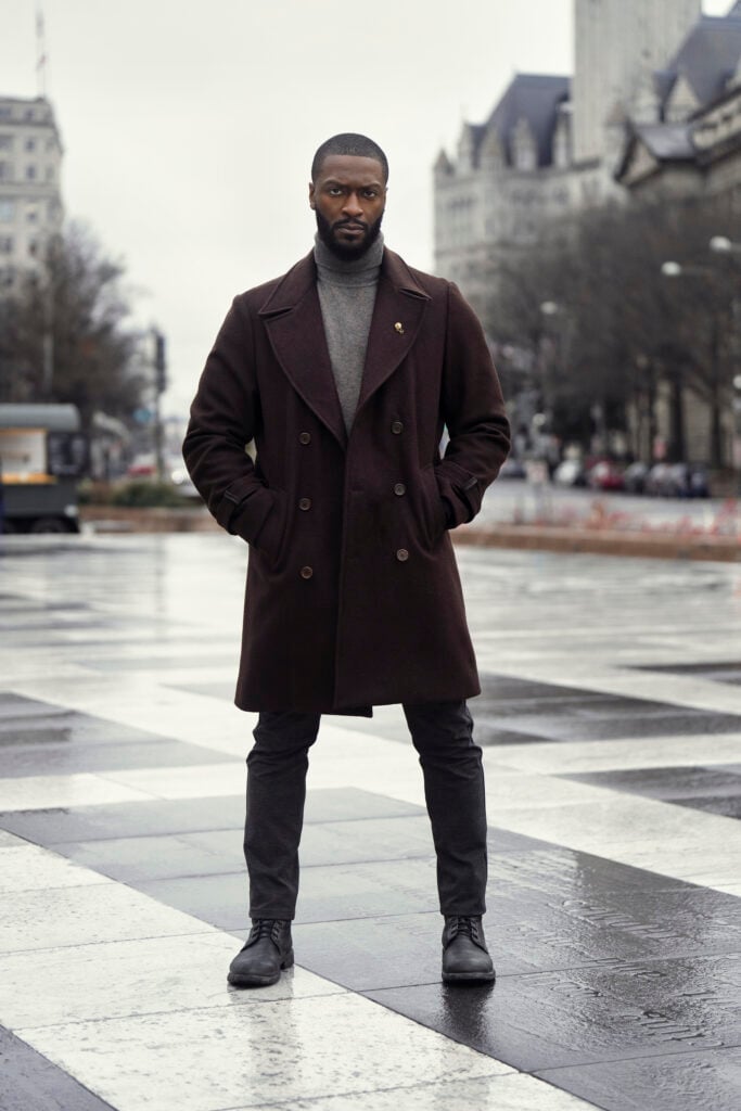 Aldis Hodge poses facing the camera in a black coat as he stars as Alex Cross in Cross.