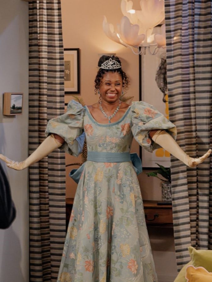 Olivia in Regency dress grins in front of curtains