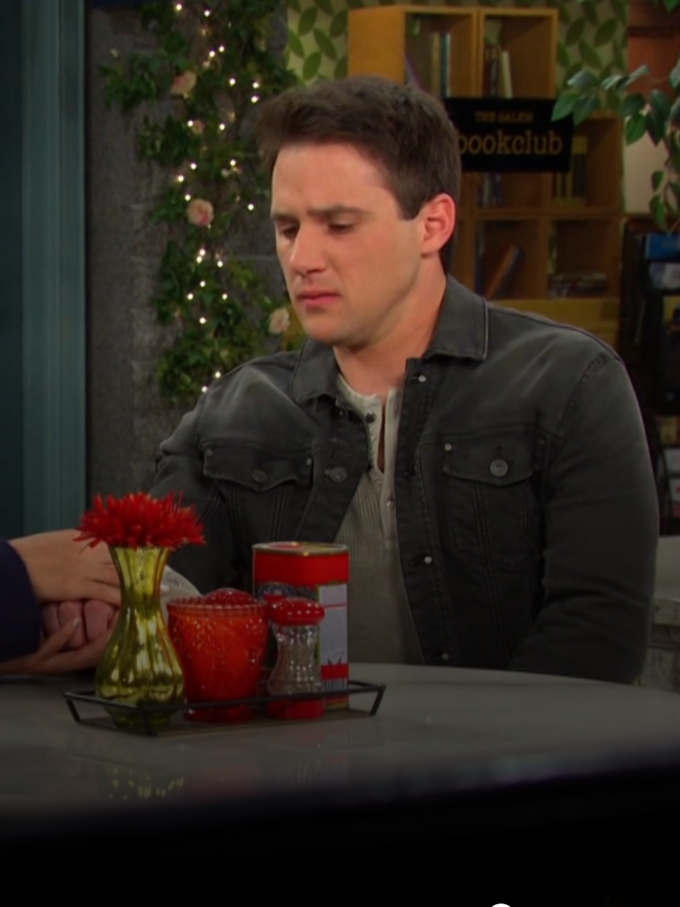 Gabi sitting with her hand over JJ's at a table in the Square on Days of Our Lives during the week of 11-19-24