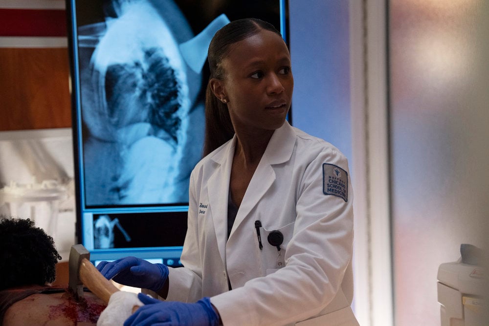 Howard looking at a monitor off-screen while removing an ax from someone's back on Chicago Med Season 10 Episode 7