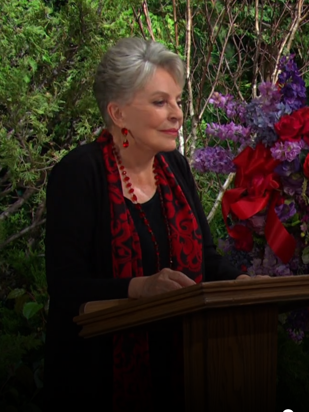 Julie stands behind the podium in the garden where Doug's funeral is being held on Days of Our Lives