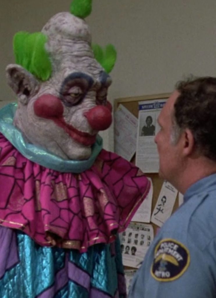 An alien clown stands off with a police officer.