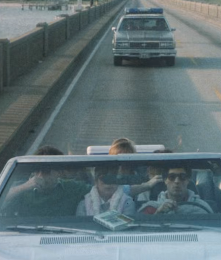 A police car follows the college students who are on their way to a lake house getaway.